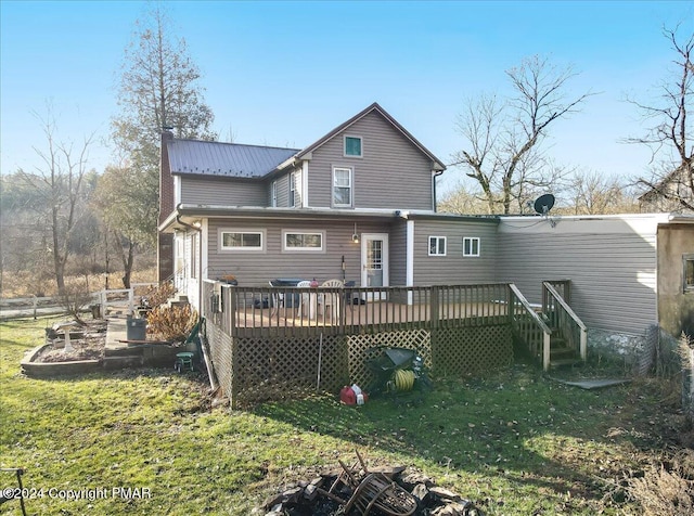 back of property with a deck, metal roof, and a lawn