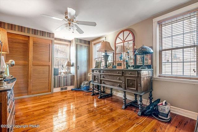 interior space featuring baseboards, visible vents, ceiling fan, and hardwood / wood-style floors