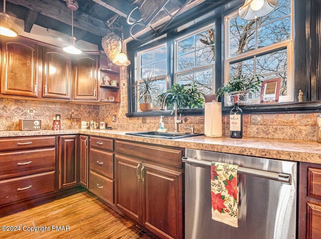 kitchen with light countertops, light wood-style flooring, decorative backsplash, a sink, and dishwasher