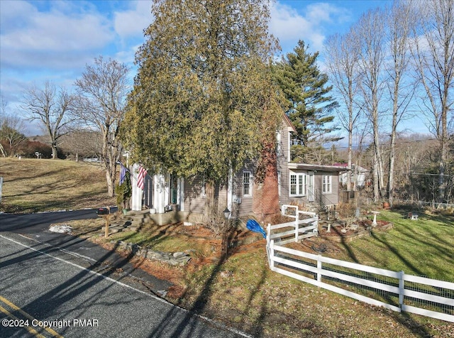 view of property hidden behind natural elements with fence and a front yard