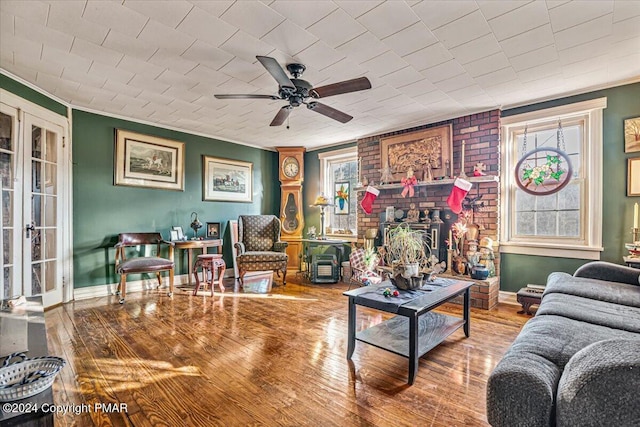 living area featuring ornamental molding, a ceiling fan, baseboards, and wood finished floors