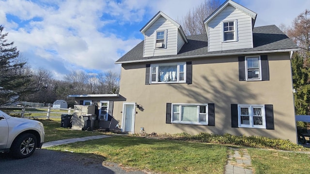 view of home's exterior featuring a lawn, a shingled roof, and stucco siding