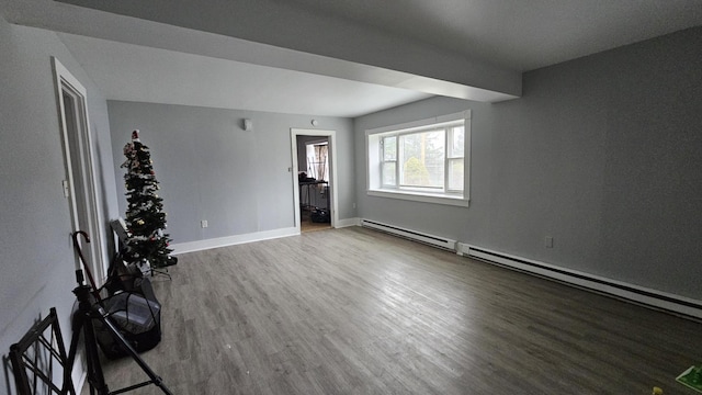 spare room with baseboards, wood finished floors, and a baseboard radiator
