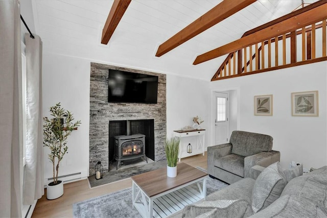 living room featuring lofted ceiling with beams, a baseboard heating unit, wood finished floors, and a wood stove