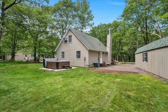 rear view of property with a patio, a chimney, a lawn, and a hot tub