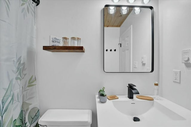 bathroom featuring a sink, toilet, and a shower with curtain