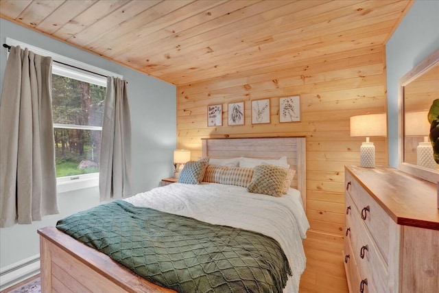 bedroom with wood walls, wood ceiling, baseboard heating, and light wood-style flooring