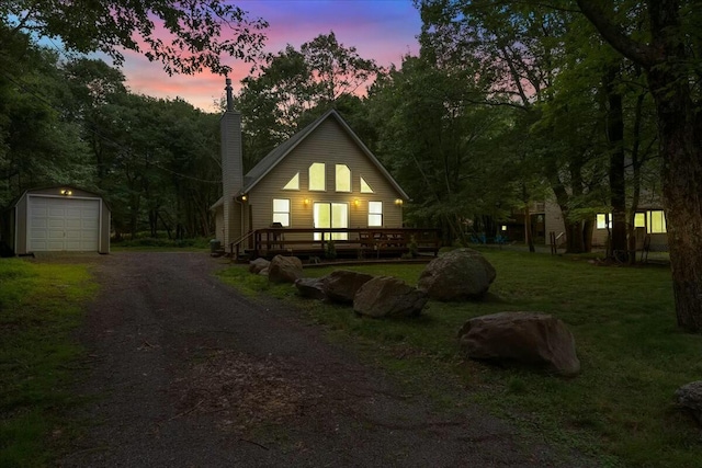 view of front of home with a garage, an outdoor structure, dirt driveway, a front lawn, and a chimney