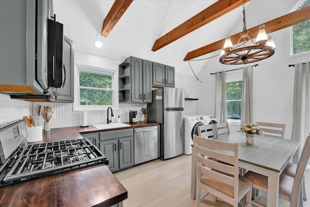 kitchen featuring washer and clothes dryer, a sink, gray cabinets, stainless steel appliances, and backsplash