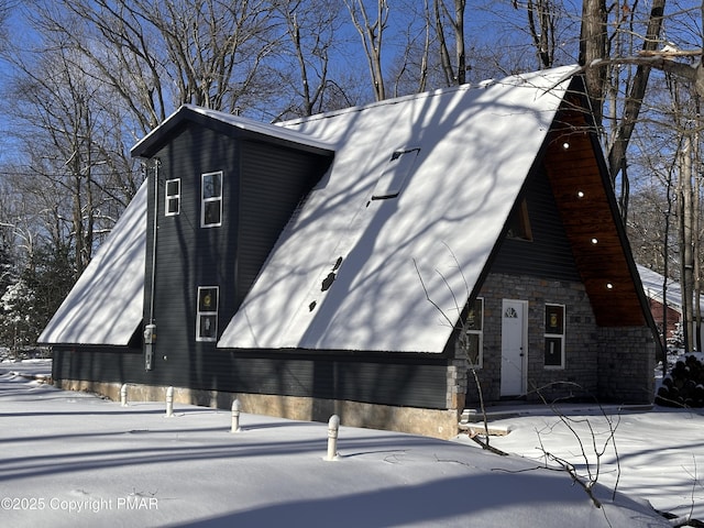 snow covered property with stone siding