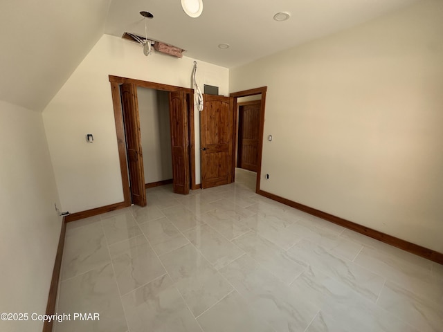 unfurnished bedroom featuring marble finish floor, vaulted ceiling, and baseboards