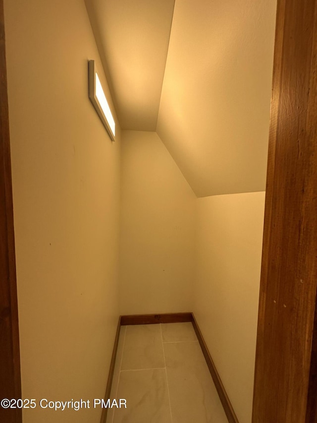 interior space featuring lofted ceiling, tile patterned floors, and baseboards