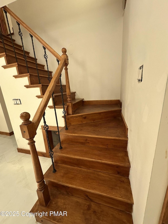 staircase featuring baseboards and wood finished floors