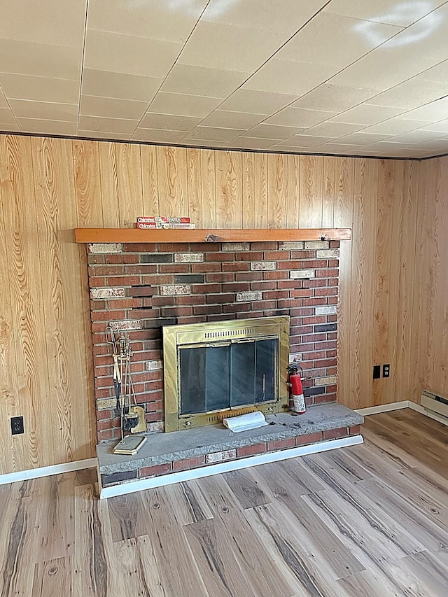 room details with wooden walls, baseboards, baseboard heating, a fireplace, and wood finished floors