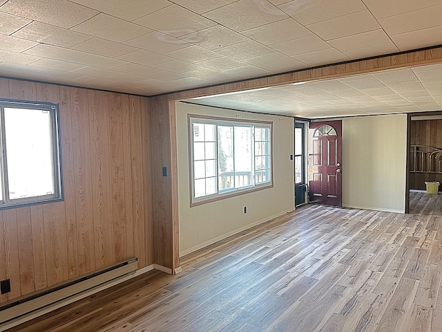 interior space with wood walls, wood finished floors, baseboards, and a baseboard radiator