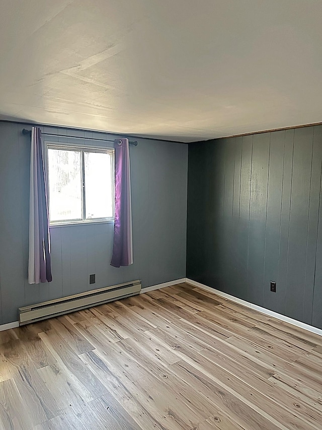 empty room with light wood-type flooring and a baseboard radiator