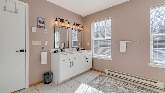 bathroom with a sink, a baseboard heating unit, double vanity, and tile patterned flooring