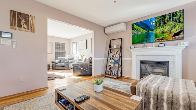 living room featuring baseboards, wood finished floors, a high end fireplace, and a wall unit AC