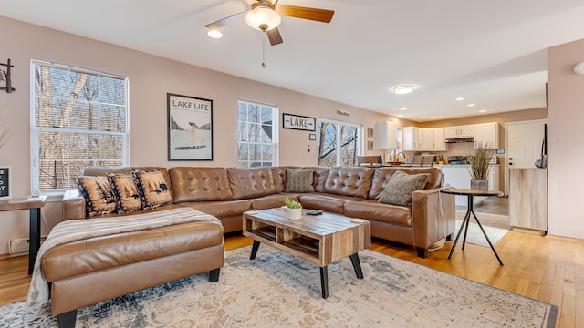 living room with recessed lighting, light wood-style floors, baseboard heating, and a ceiling fan