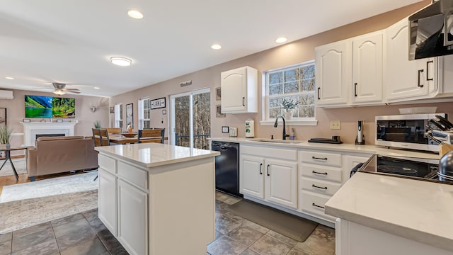 kitchen featuring stainless steel microwave, range with electric cooktop, a center island, black dishwasher, and a sink