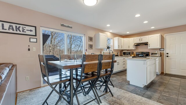 kitchen featuring a kitchen island, electric range, white cabinets, under cabinet range hood, and stainless steel microwave