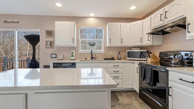 kitchen featuring under cabinet range hood, white cabinetry, black appliances, and a sink