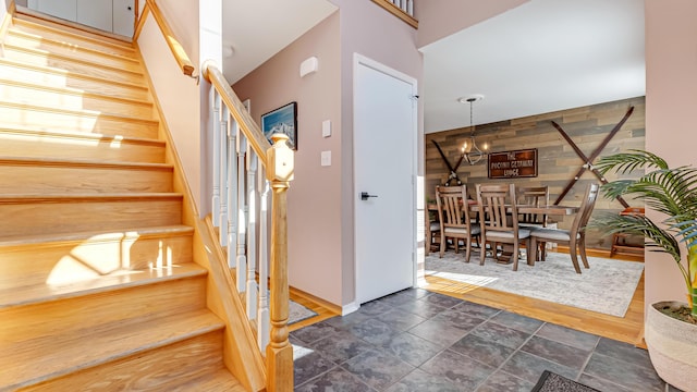 stairway with wooden walls, a notable chandelier, and stone finish flooring