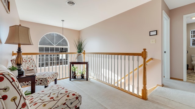 hall featuring an upstairs landing, visible vents, baseboards, and carpet