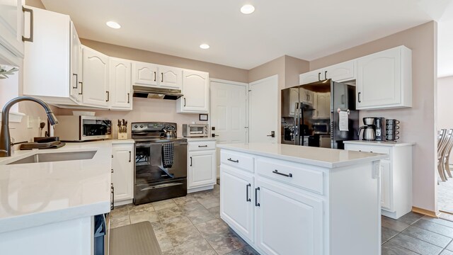 kitchen with under cabinet range hood, black appliances, white cabinets, and a sink