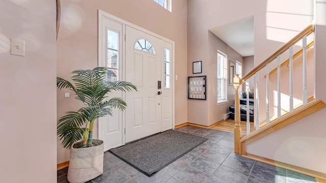 foyer featuring stairs, baseboards, and a towering ceiling