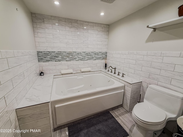 bathroom featuring tile walls, a tub, and toilet