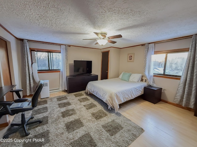 bedroom featuring crown molding, a textured ceiling, ceiling fan, and light hardwood / wood-style floors