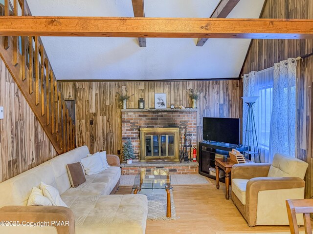 living room with a fireplace, lofted ceiling with beams, light hardwood / wood-style flooring, and wood walls