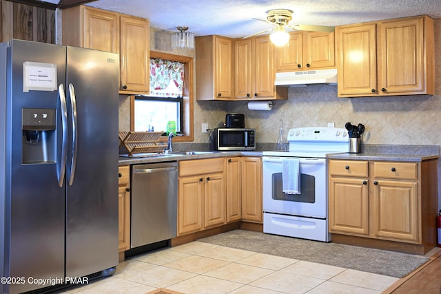 kitchen with sink, tasteful backsplash, light tile patterned floors, appliances with stainless steel finishes, and ceiling fan