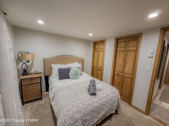 bedroom featuring light carpet and two closets