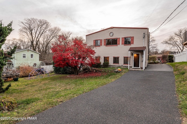 traditional-style home with a front lawn, fence, and aphalt driveway