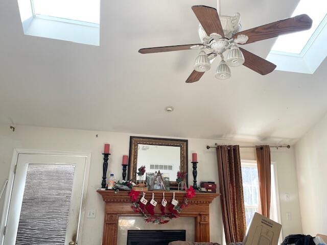 interior details featuring a fireplace, a skylight, and a ceiling fan