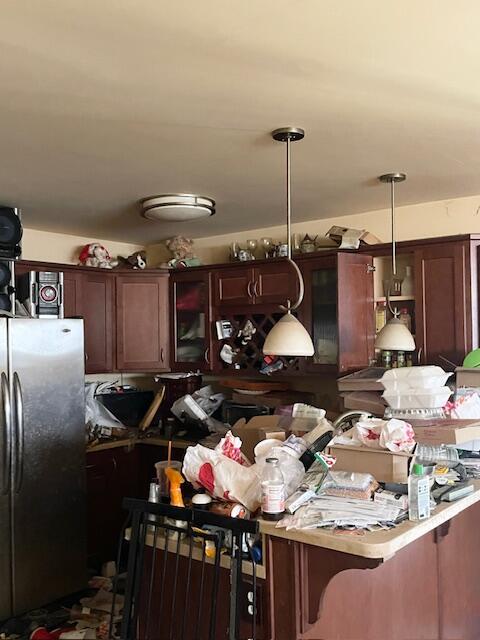 kitchen featuring dark brown cabinetry, decorative light fixtures, and freestanding refrigerator