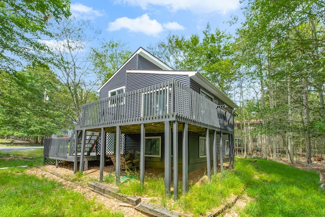 back of property with a lawn, a wooden deck, and stairway