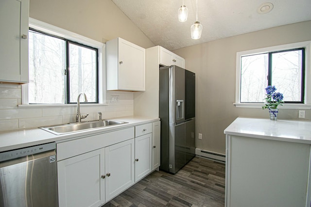 kitchen featuring dark wood-style floors, stainless steel appliances, a sink, a baseboard heating unit, and decorative backsplash