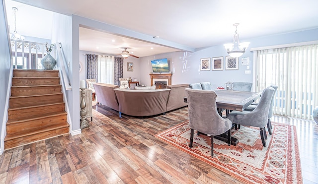 6435 Marvin Gdns, Tobyhanna, PA 18466 - dining space featuring wood finished floors, stairway, beam ceiling, a lit fireplace, and a chandelier
