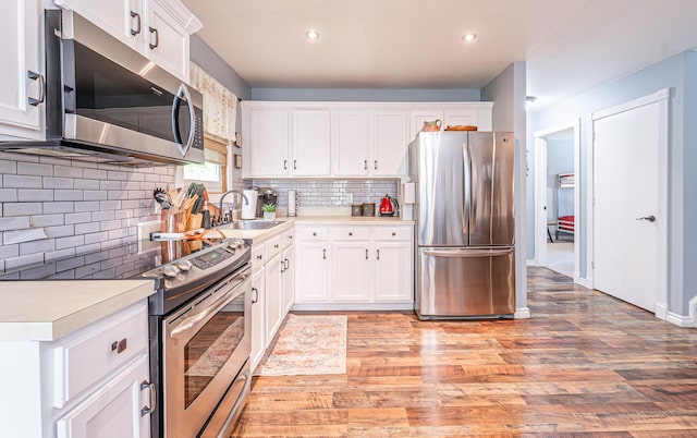 6435 Marvin Gdns, Tobyhanna, PA 18466 - kitchen featuring stainless steel appliances, a sink, light countertops, decorative backsplash, and light wood-type flooring