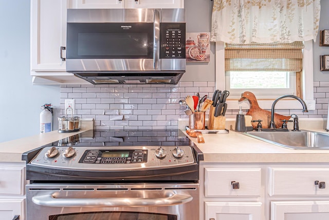 6435 Marvin Gdns, Tobyhanna, PA 18466 - kitchen featuring stainless steel appliances, a sink, white cabinets, backsplash, and light countertops