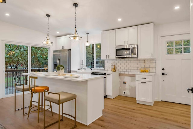19 Mckinley Ln, Albrightsville, PA 18210 - kitchen with stainless steel appliances, white cabinetry, a kitchen breakfast bar, decorative backsplash, and light wood-type flooring