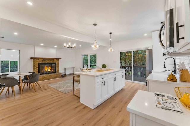 19 Mckinley Ln, Albrightsville, PA 18210 - kitchen featuring a fireplace, light wood-style flooring, white cabinetry, stainless steel microwave, and light countertops