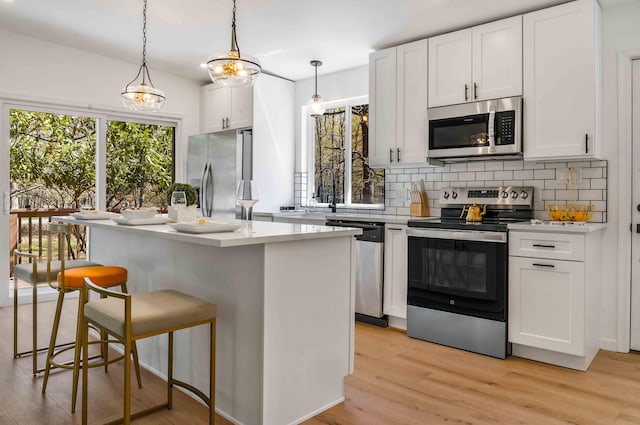 19 Mckinley Ln, Albrightsville, PA 18210 - kitchen with stainless steel appliances, light wood finished floors, tasteful backsplash, a breakfast bar area, and white cabinetry