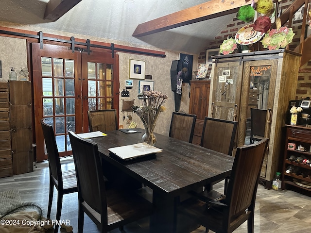 dining room featuring a barn door, vaulted ceiling, and a textured ceiling