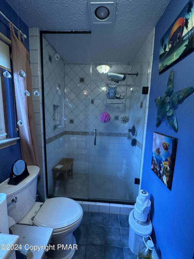 bathroom with vanity, a shower stall, toilet, and a textured ceiling