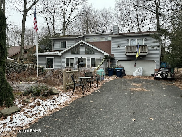 view of front of home with driveway, a chimney, and an attached garage