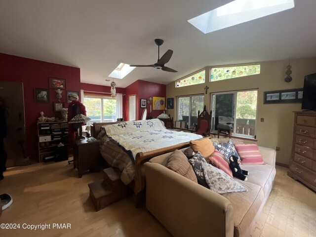 bedroom with lofted ceiling with skylight, light wood-style flooring, access to outside, and a ceiling fan